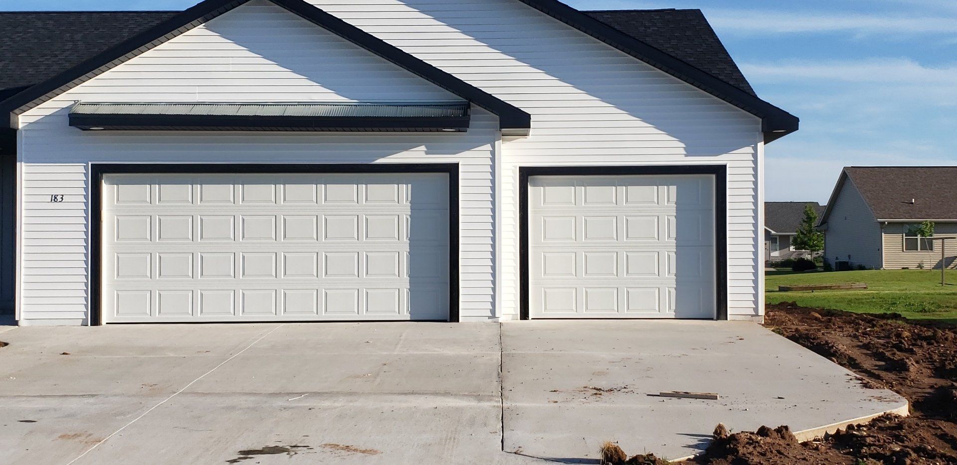 New house exterior with a double garage and single garage door on a concrete driveway