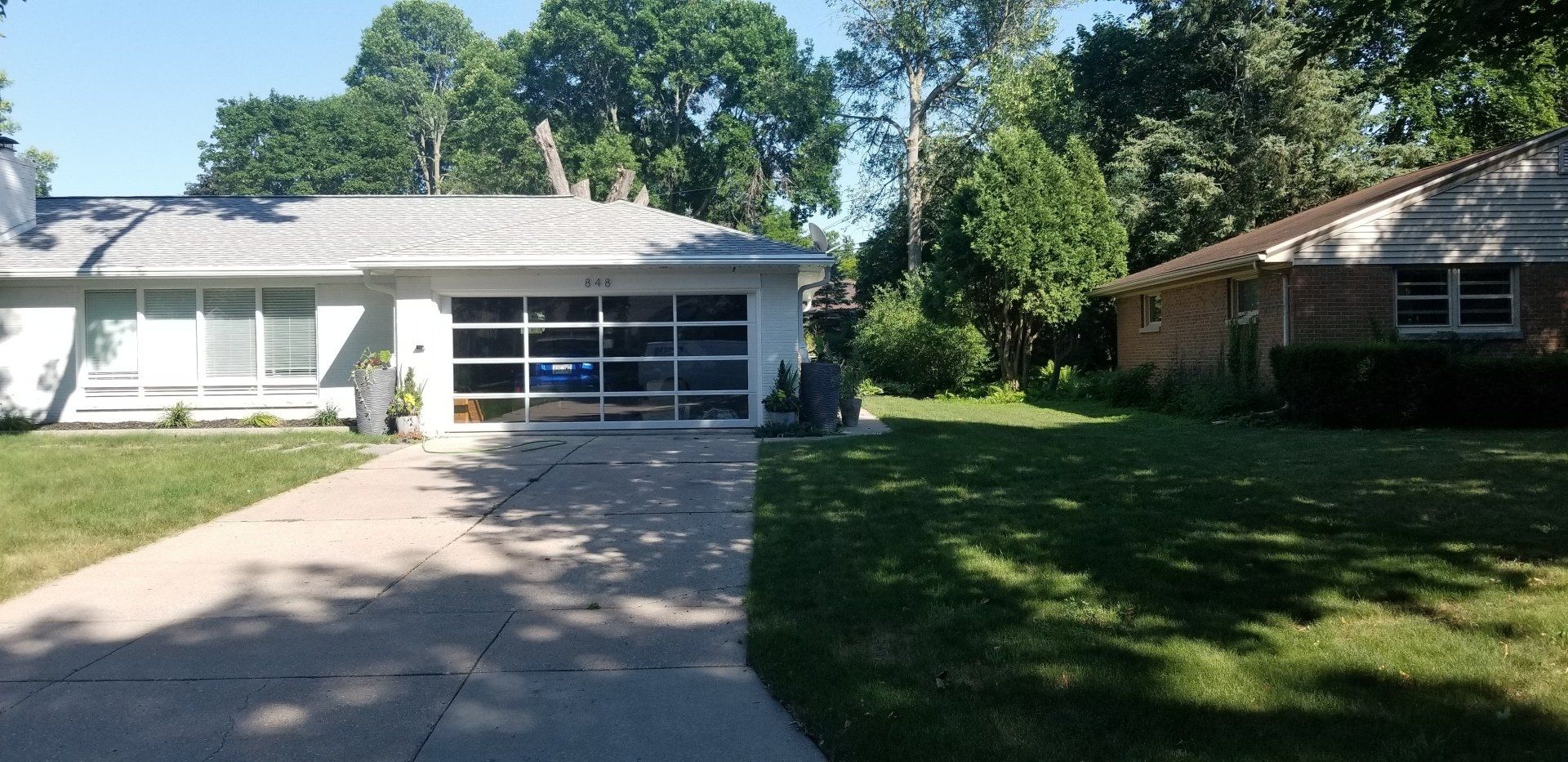 Suburban house with a driveway, garage, and trees in the front yard