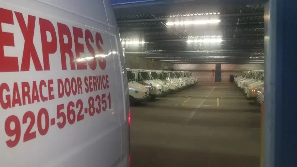 Service van with “EXPRESS Garage Door Service” beside a long indoor parking garage aisle
