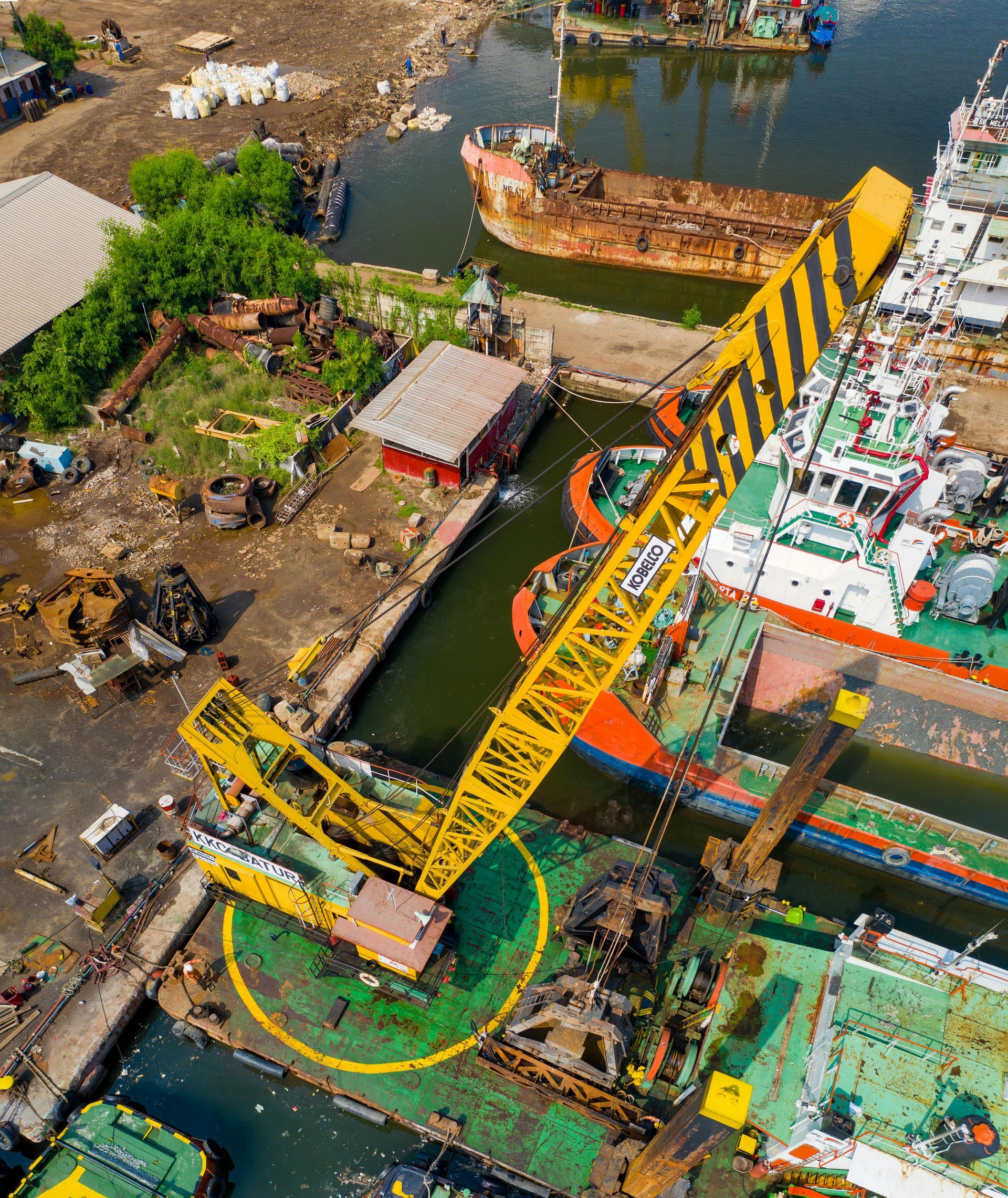 Aerial view of a yellow crane over a canal beside docks, boats, and buildings.