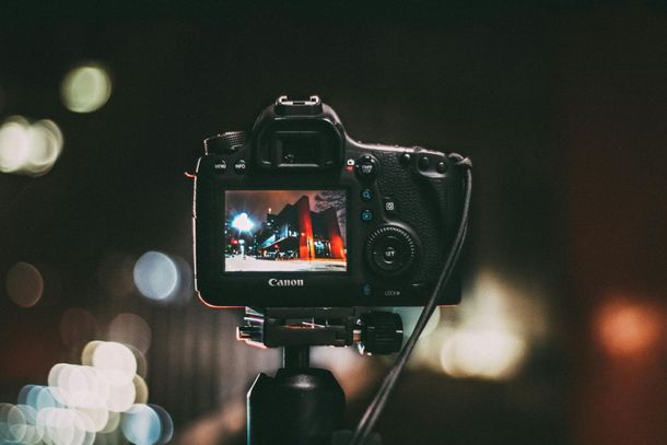 Camera on tripod filming a concert with blurred city lights in the background