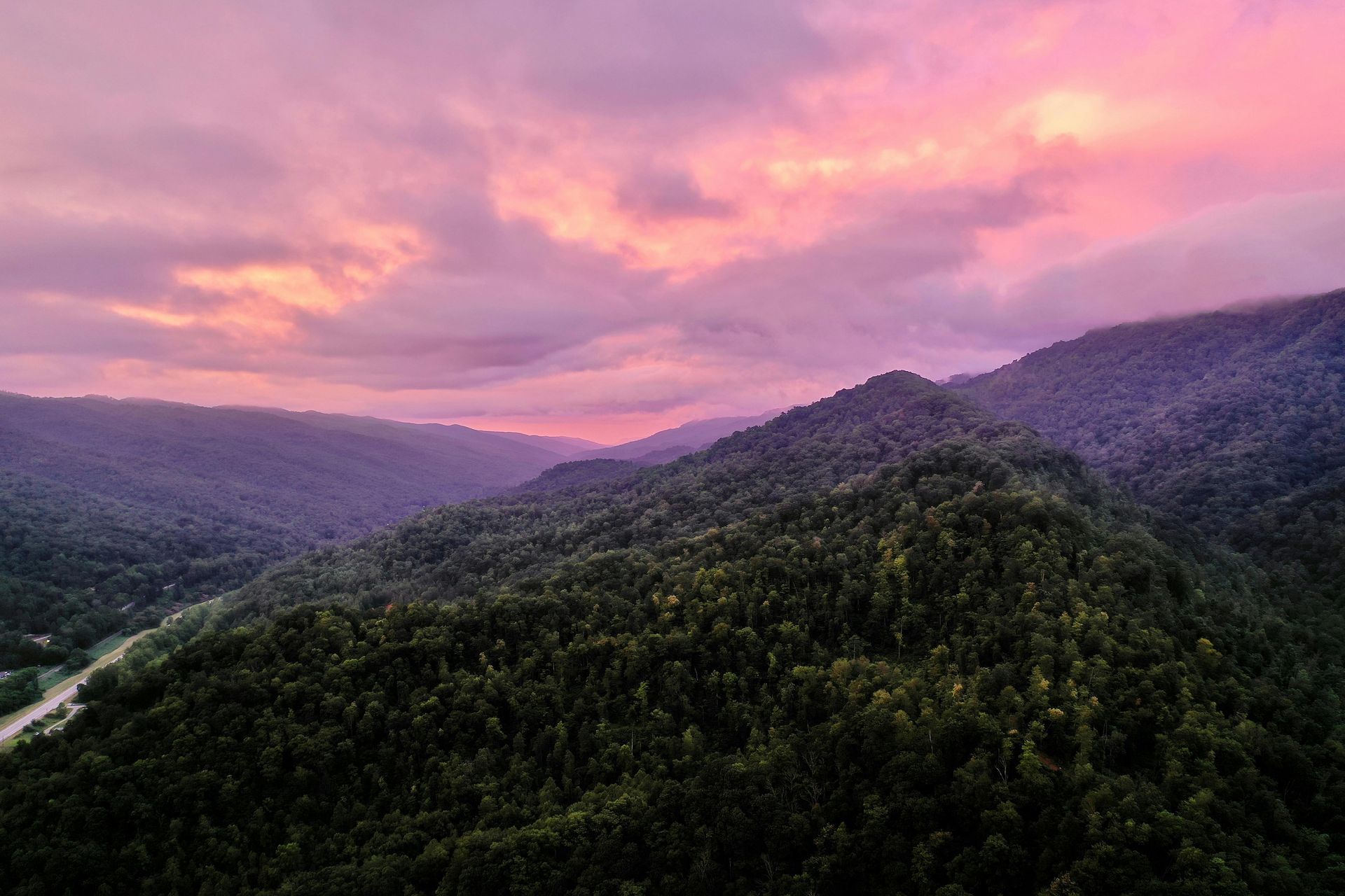 Pink sunset over forested mountains and valleys