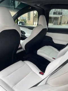 White and black car interior with sleek seats and city buildings visible through the windows