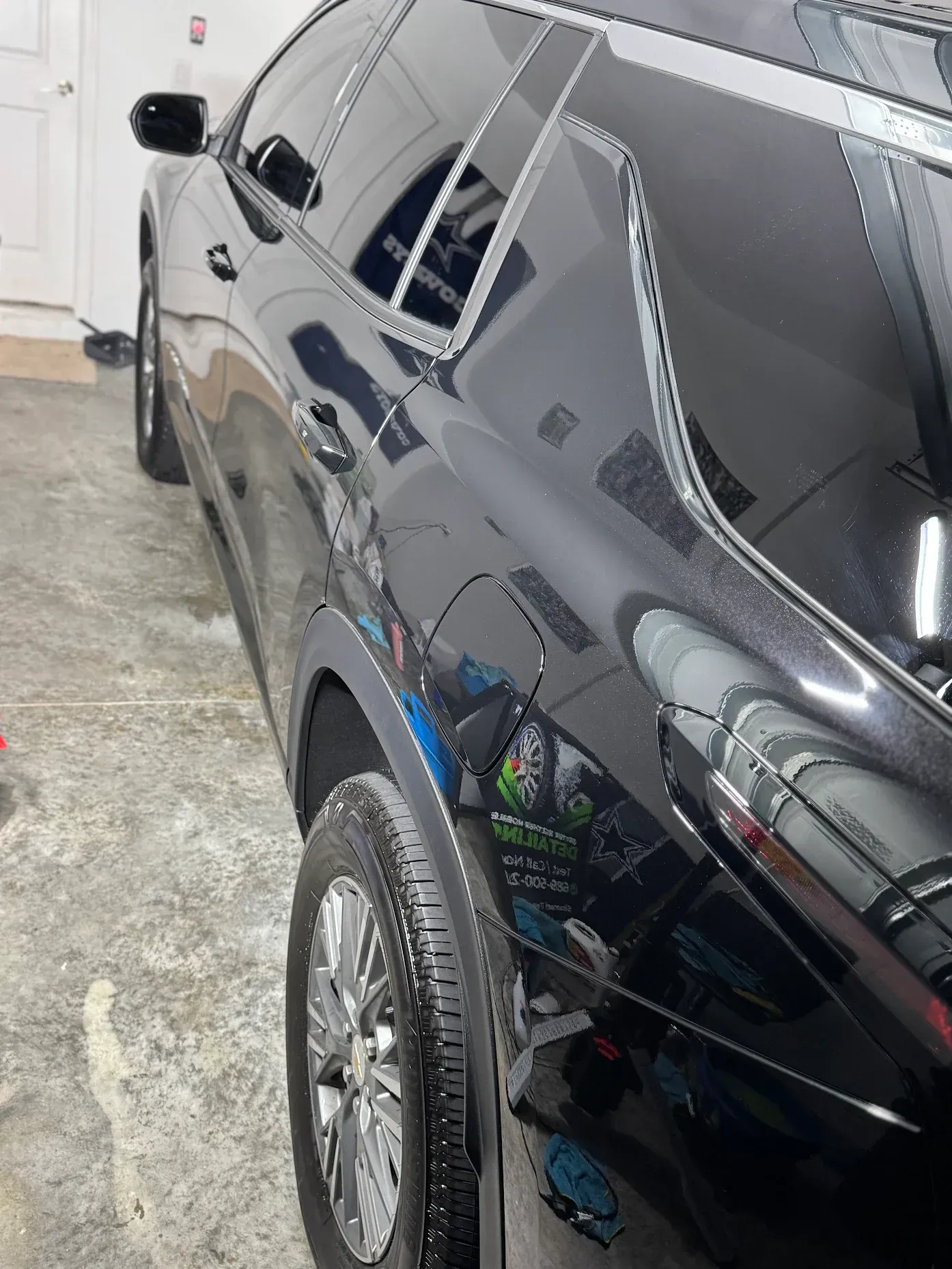 Black SUV parked in a garage, side view with tinted windows and chrome wheels