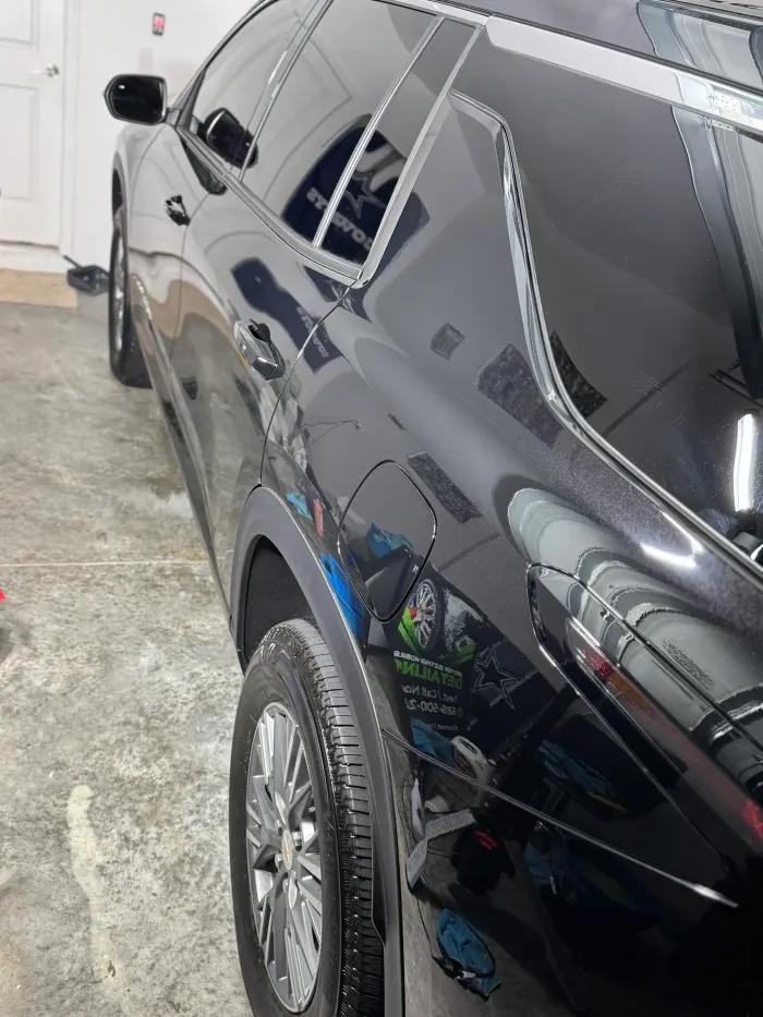 Black SUV parked in a garage, side view with tinted windows and chrome wheels