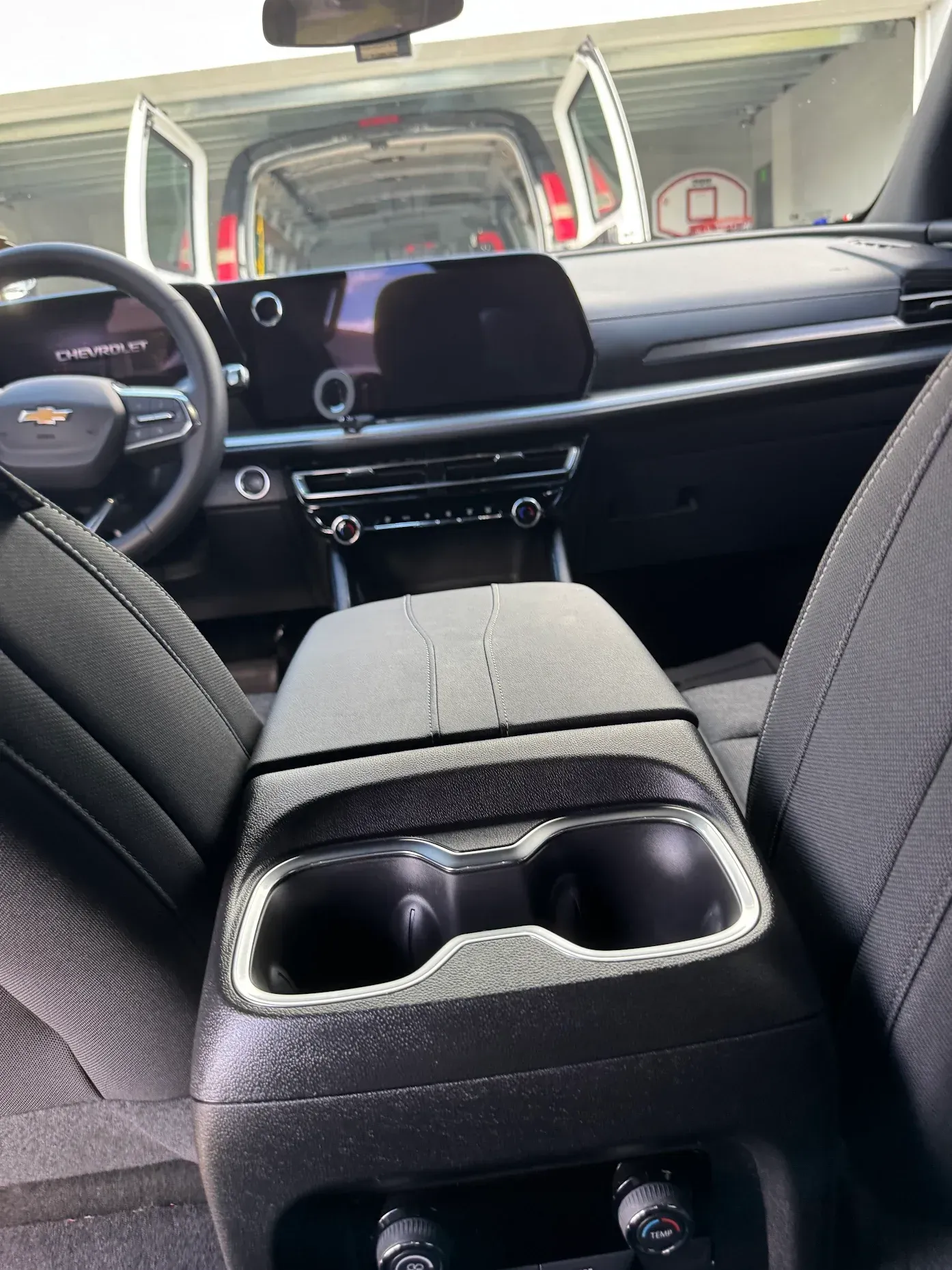 Car interior with rear seats folded down, showing a center armrest and front dashboard view.