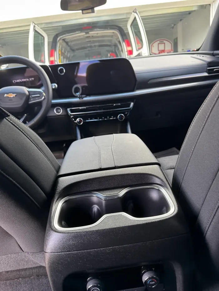 Car interior with rear seats folded down, showing a center armrest and front dashboard view.