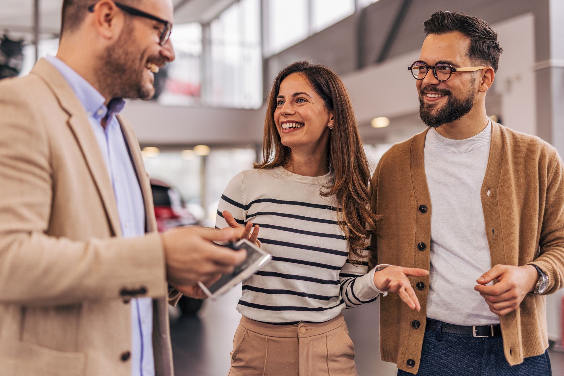 Car salesperson showing keys to a smiling couple in a dealership. Car salesperson showing keys to a smiling couple in a dealership.