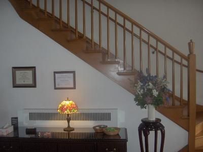 Staircase in a home entryway with framed wall art, small table lamp, and floral arrangement beneath it