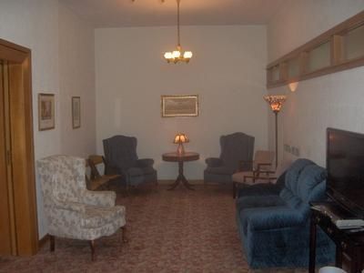 Cozy living room with patterned chairs, blue sofa, TV, and small table under warm ceiling light