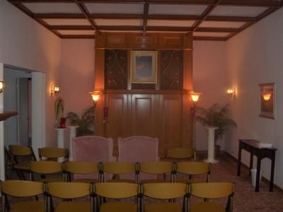 Small chapel-like room with rows of chairs facing an altar and wall sconces