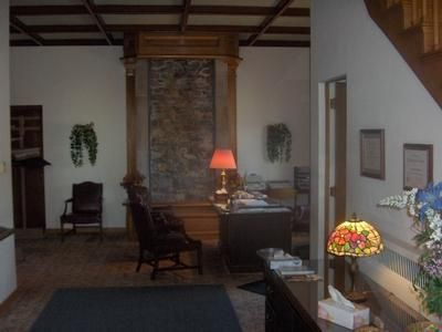 Living room with stone fireplace, desk and chair, warm lamp, stained-glass table lamp, and staircase.