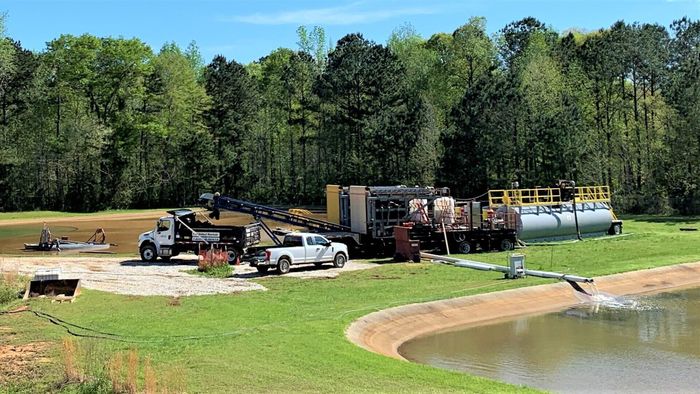 A truck is parked in a grassy field next to a pond.