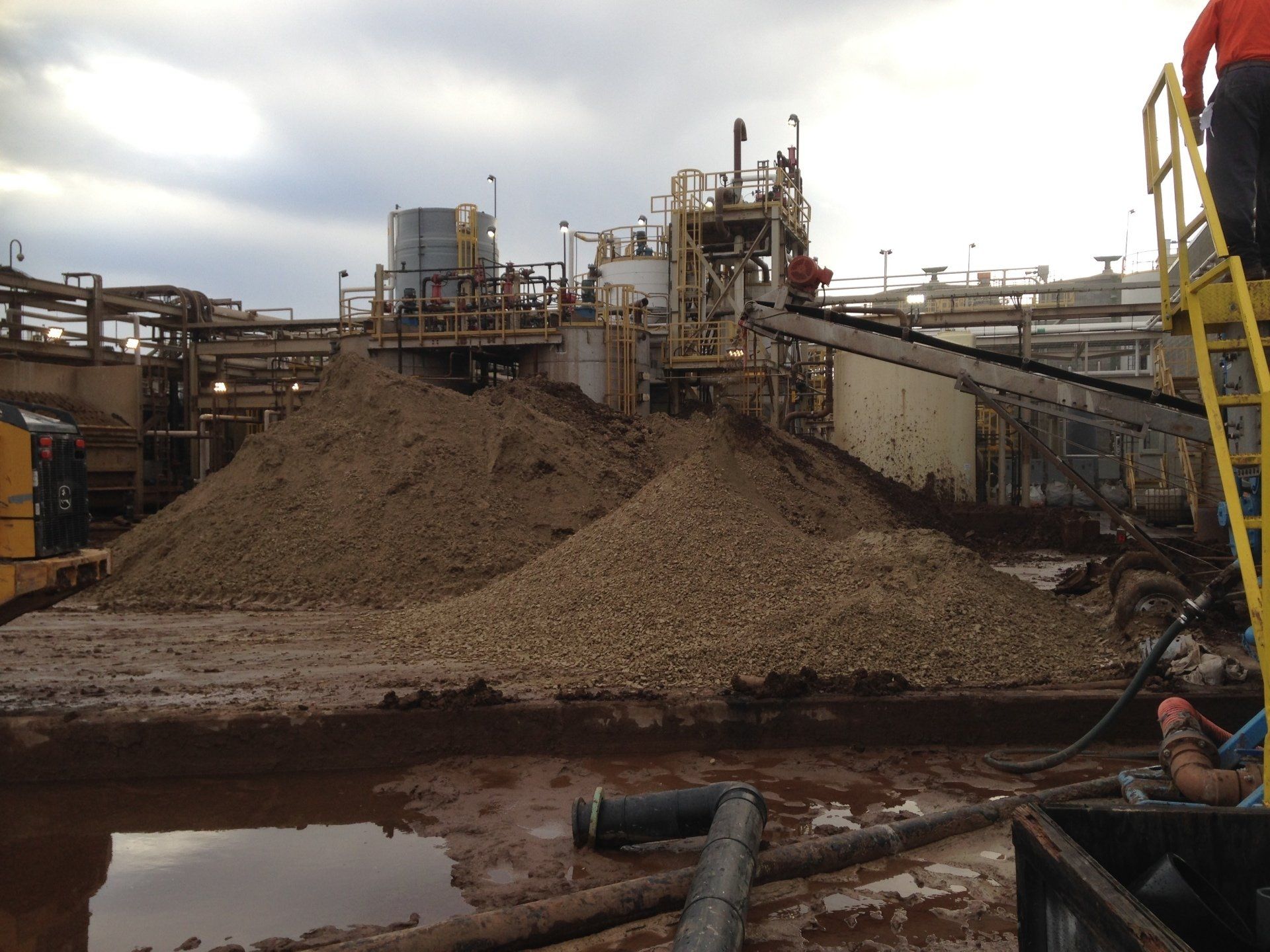 A man standing on a ladder in front of a large pile of dirt