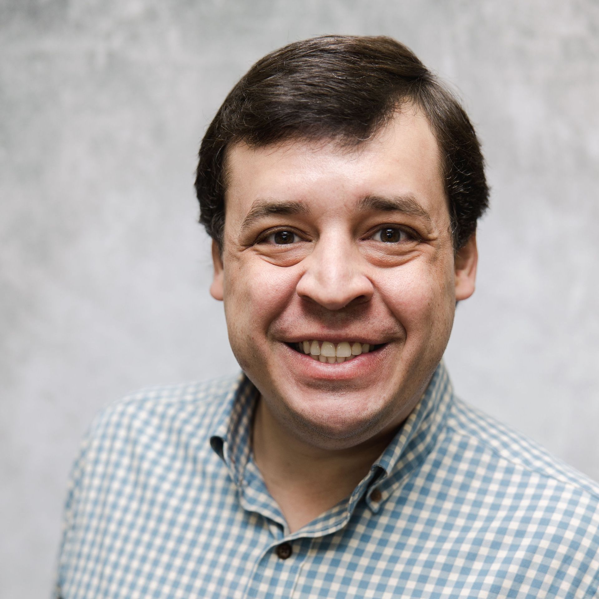 A man in a plaid shirt is smiling for the camera.