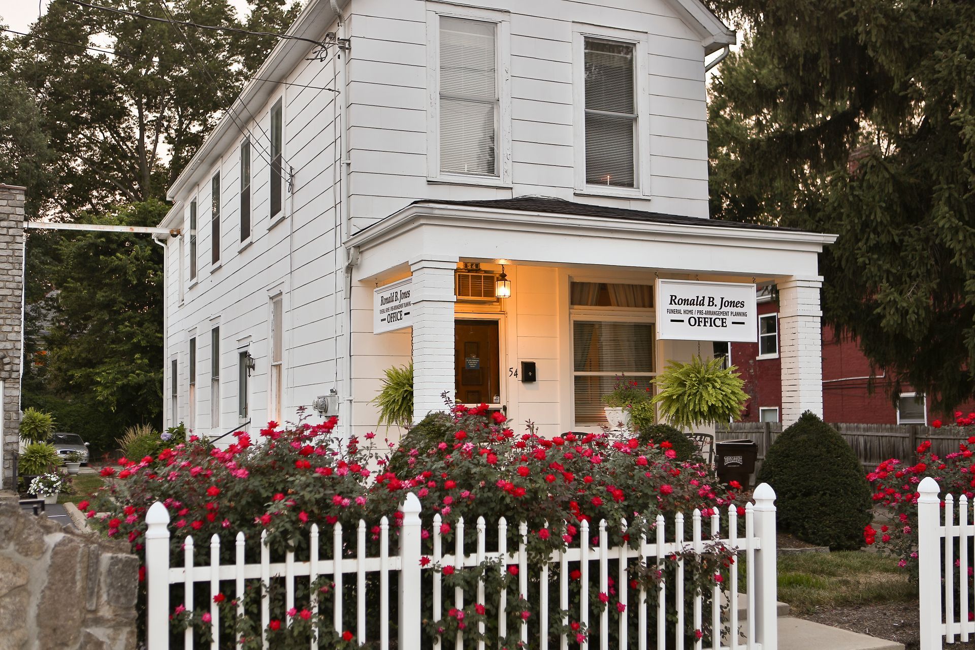 Funeral home office with red roses along the white picket fence