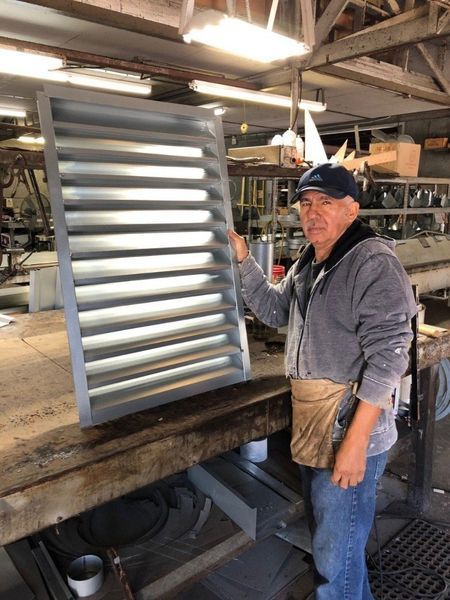 A man is standing in a room holding a piece of metal.