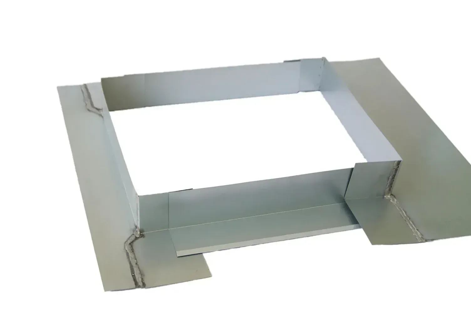 A square piece of metal is sitting on top of a white surface.