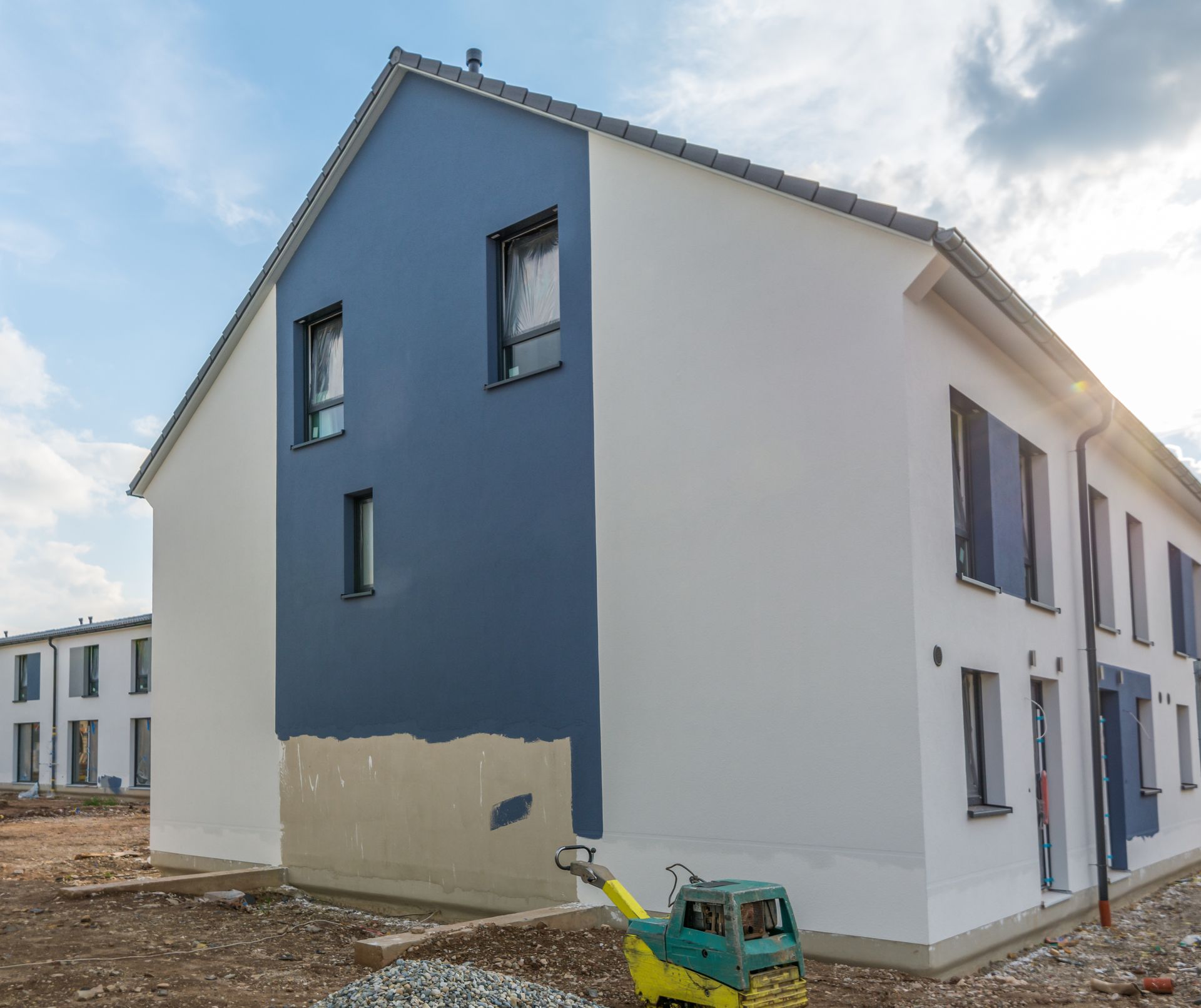Ein neues Reihenhaus im Bau mit blauer Akzentwand und weißer Fassadenverkleidung