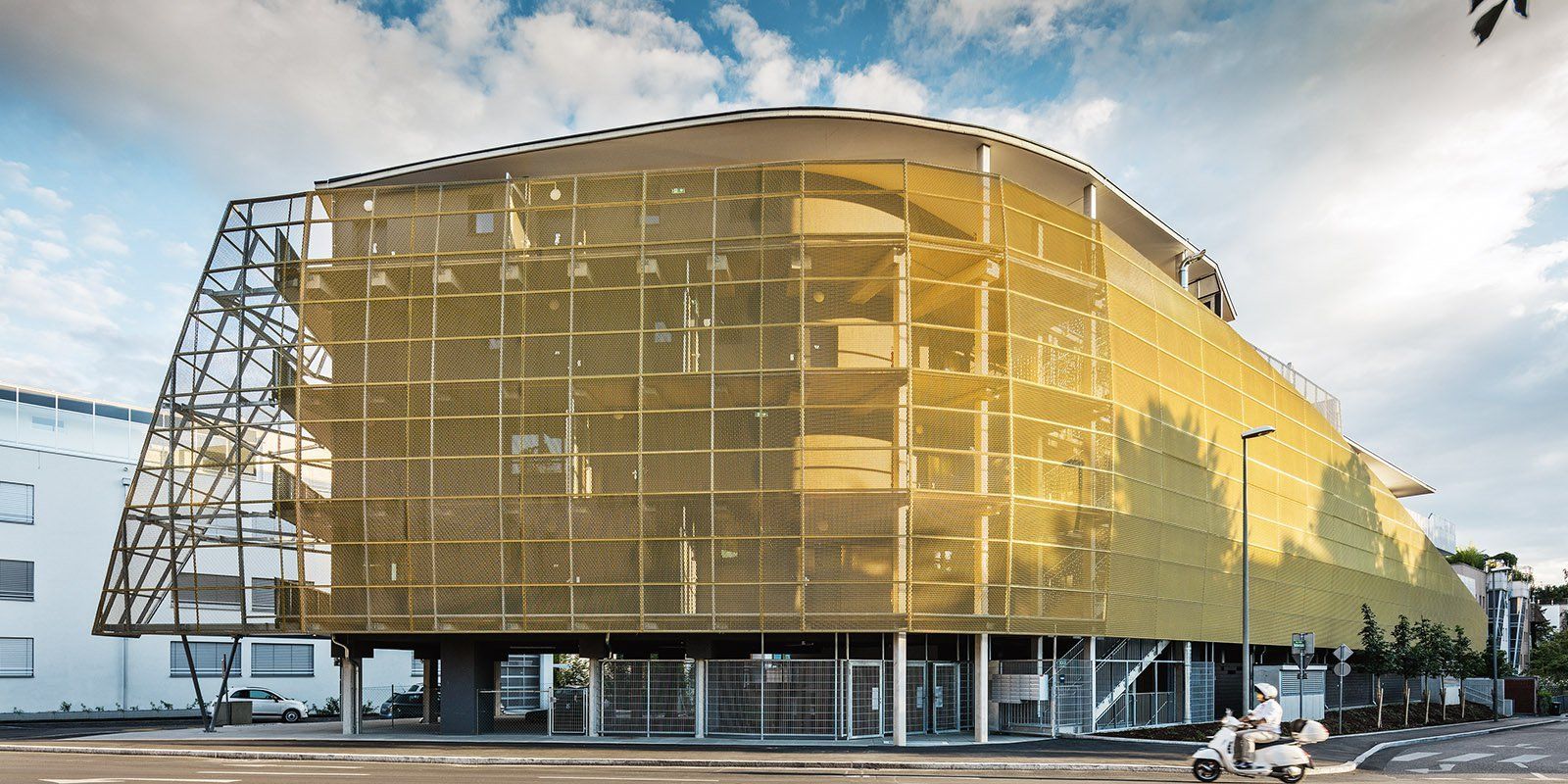 Ein mehrstöckiges Parkhaus, dessen Fassade aus gelbem, goldfarbenem Metallgewebe besteht