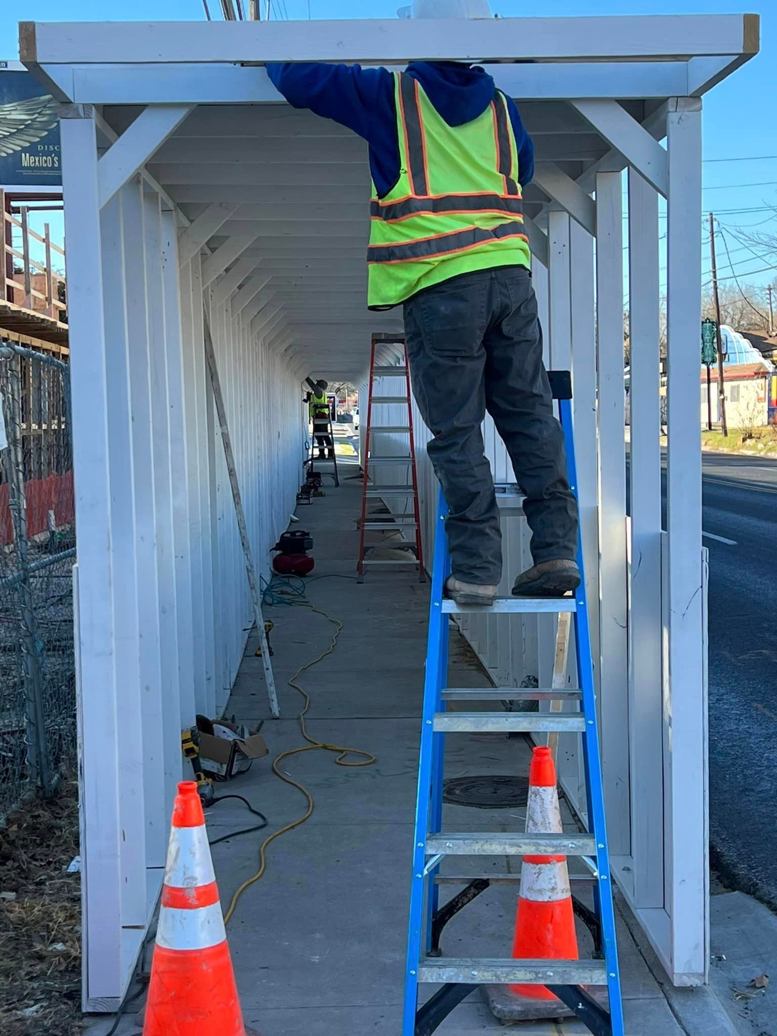A man is standing on a ladder working on a safety pedestrian walkway