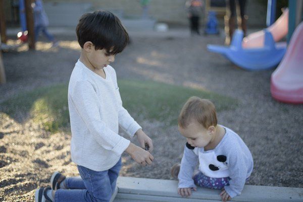 Children standing in line on a colorful playground, waiting on numbered spots.