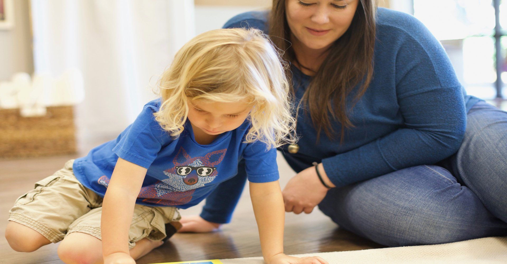 Teacher helping children draw at a classroom table with colorful supplies