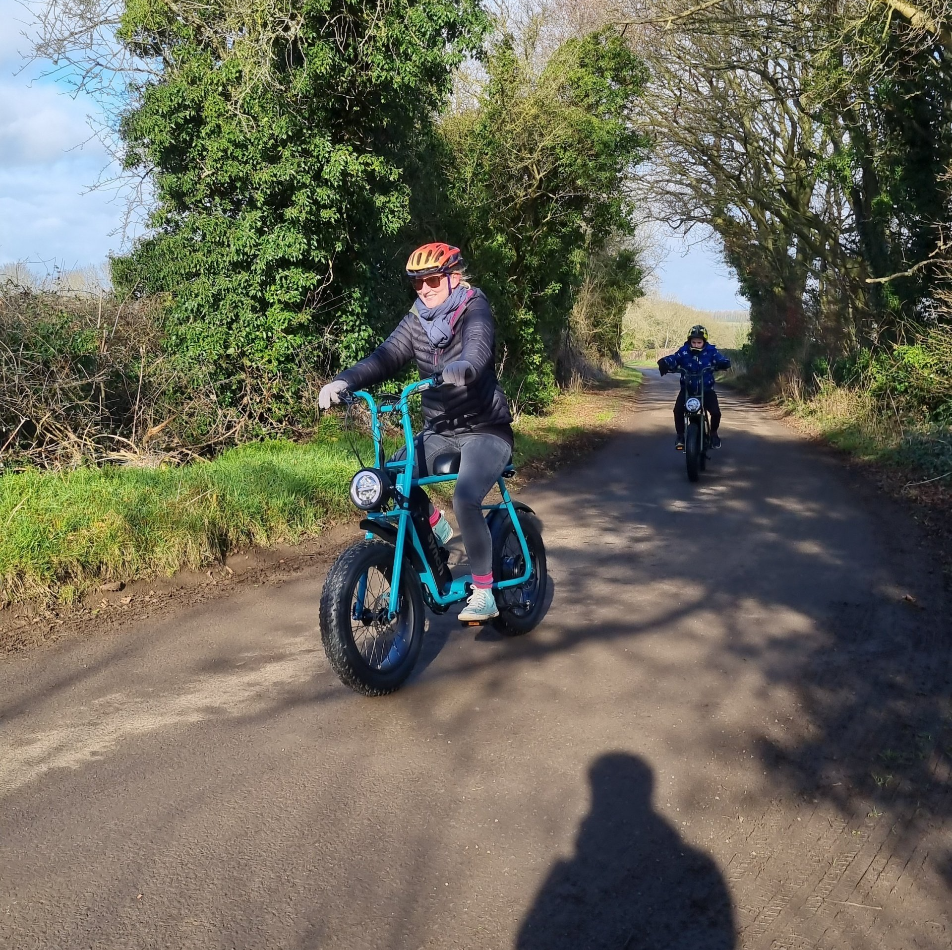 A person riding a blue scooter down a road