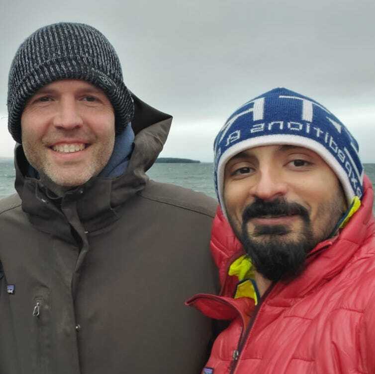 Two men posing for a picture with one wearing a patagonia hat