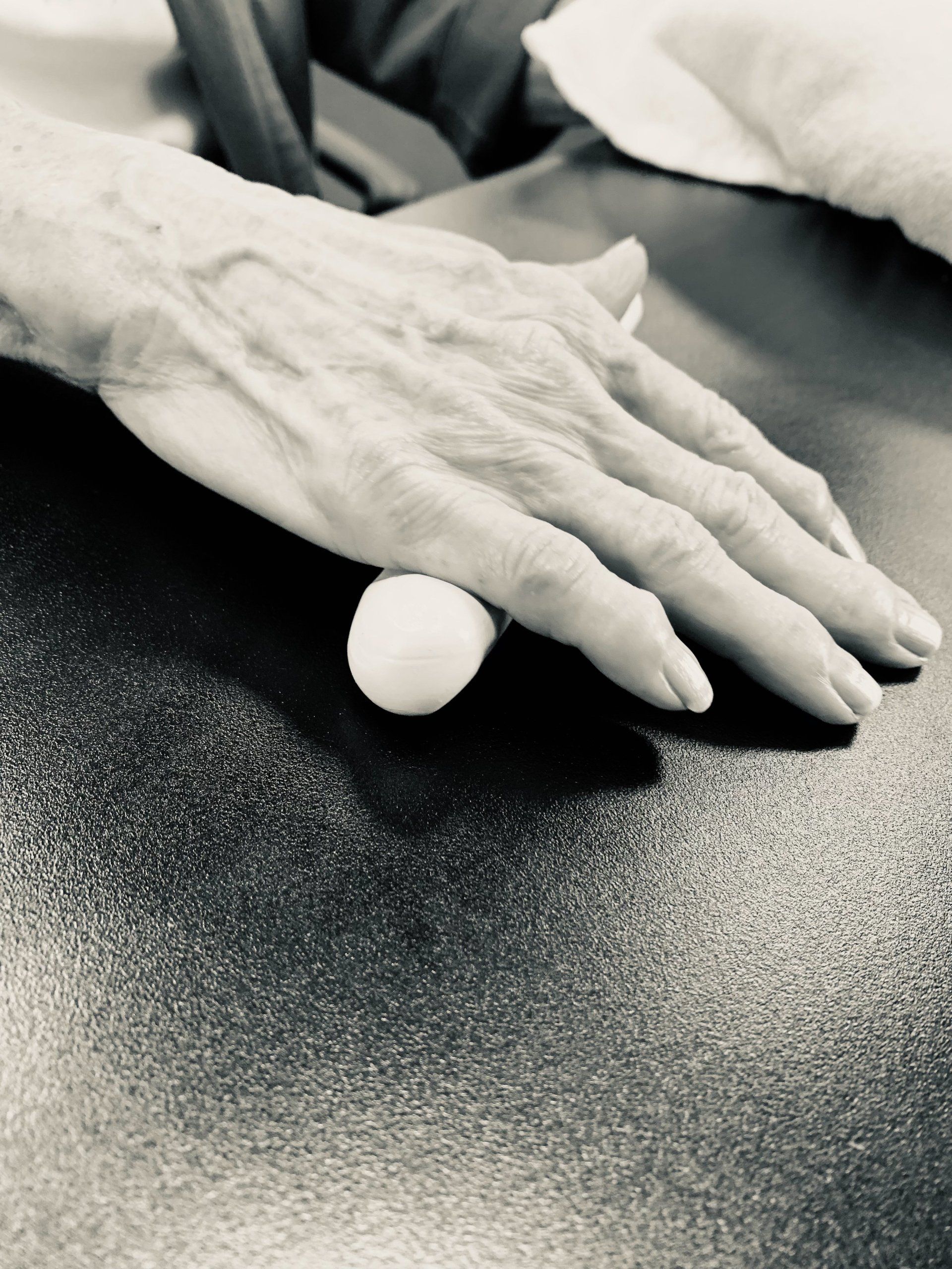 Hands rolling a small white ball across a textured dark surface