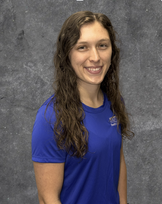 Smiling woman in a blue shirt posing against a gray studio backdrop