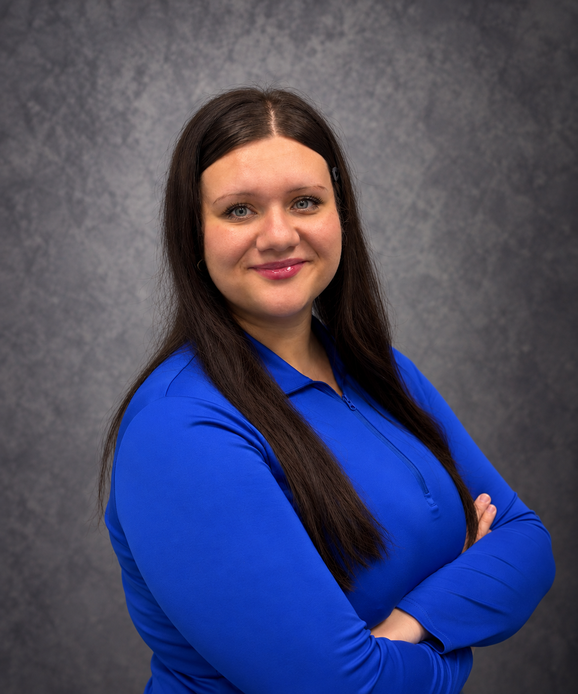 Smiling woman in a blue shirt against a gray studio backdrop
