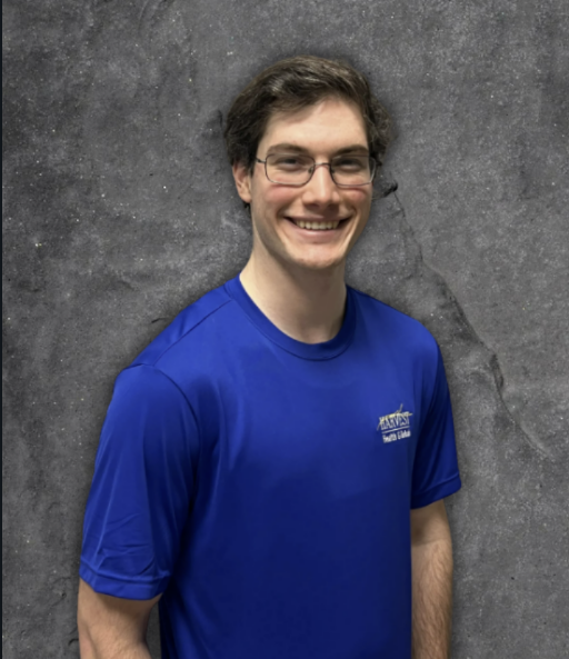 Smiling person in a blue T-shirt against a gray backdrop