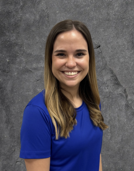 Smiling woman in a blue shirt posing against a gray studio backdrop