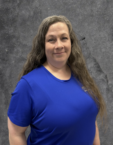 Smiling person in a royal blue shirt against a gray textured backdrop