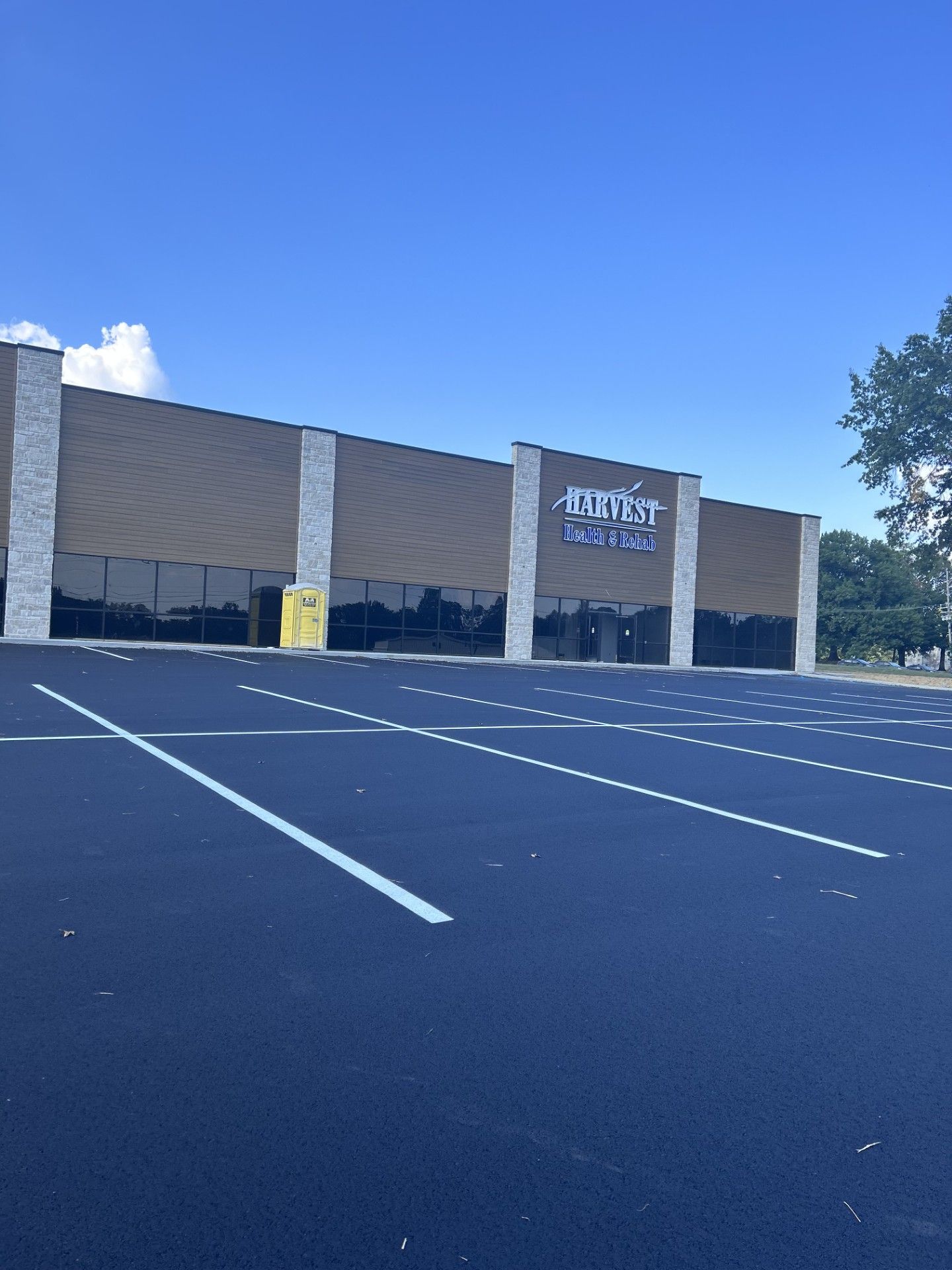 Empty parking lot in front of a storefront under a clear blue sky.