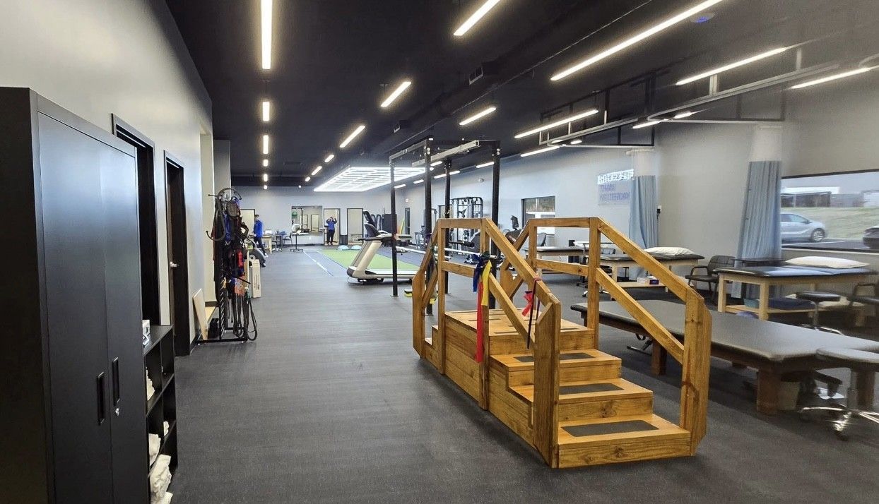 Open office with worktables, black cabinets, and a wooden staircase rail in the foreground