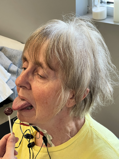 Woman in yellow shirt tasting food from a spoon indoors