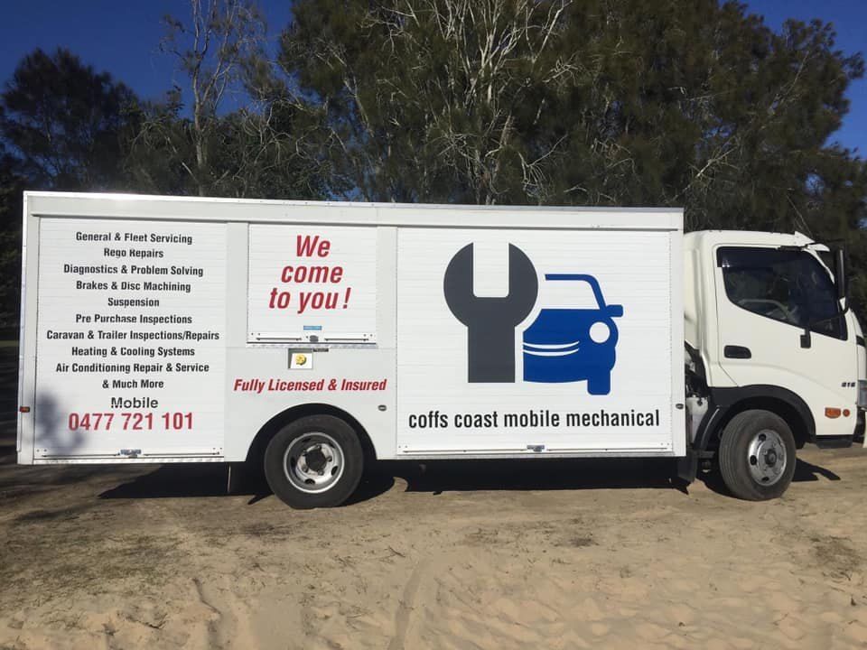 A White Truck With a Wrench on the Side is Parked in the Dirt — Coffs Coast Mobile Mechanical in Toormina, NSW