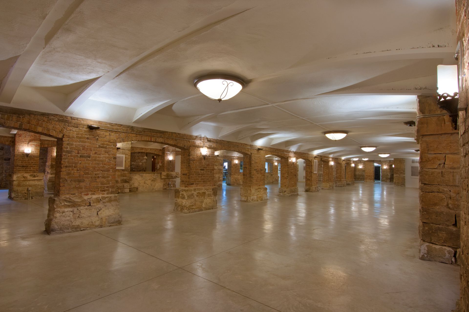 Spacious, arched interior with stone columns and a glossy floor, lit by overhead lights.