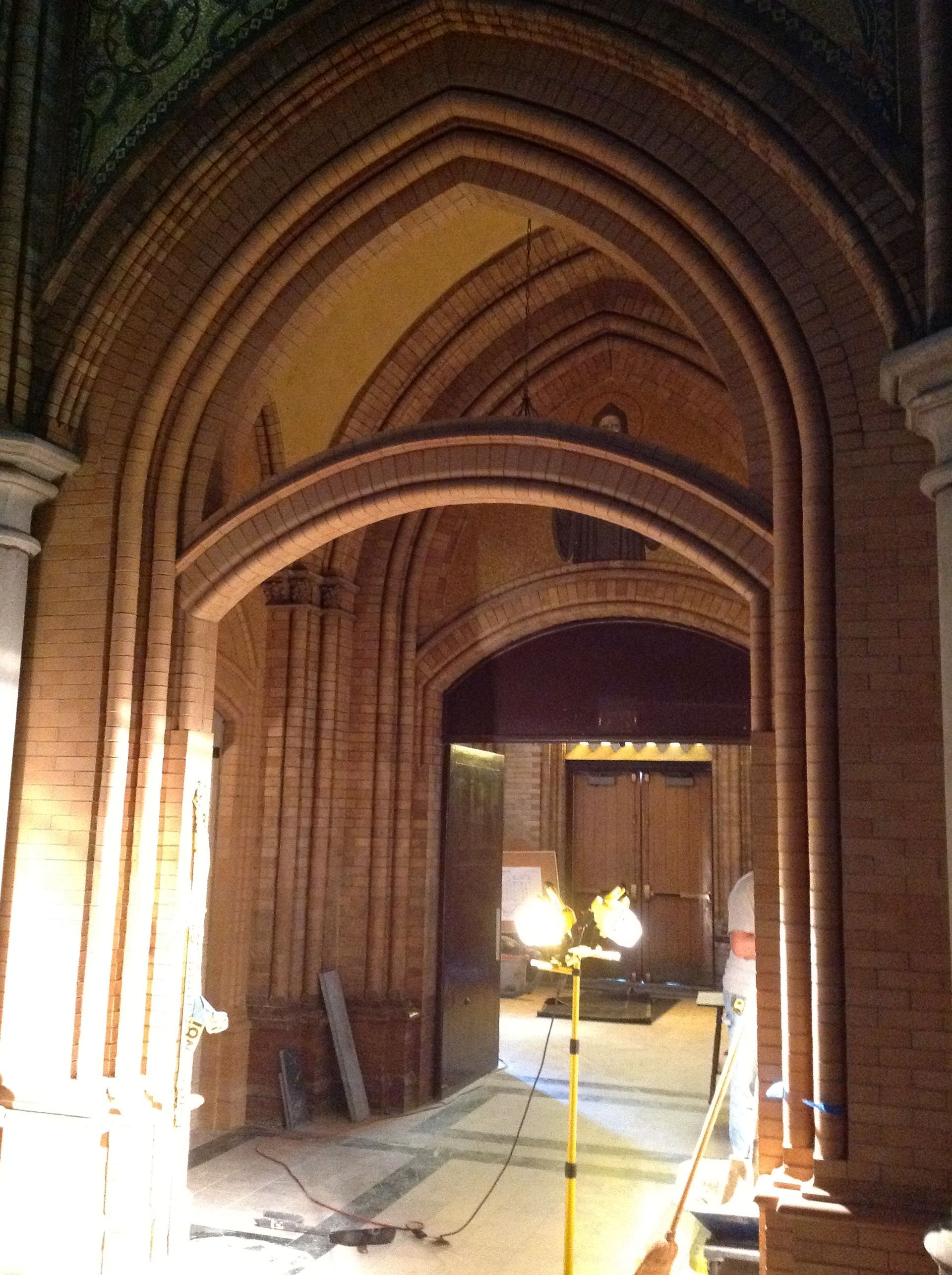 Interior view of arched doorways, red brick, lit by overhead and work lights.