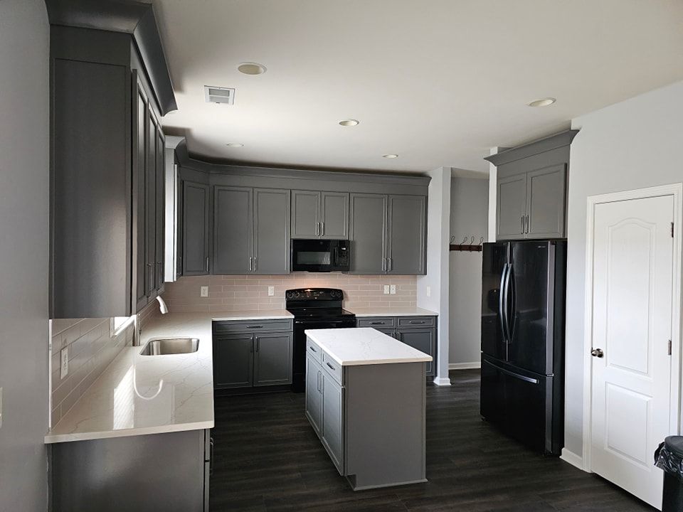 Gray kitchen with dark cabinets, white countertops, and black appliances.