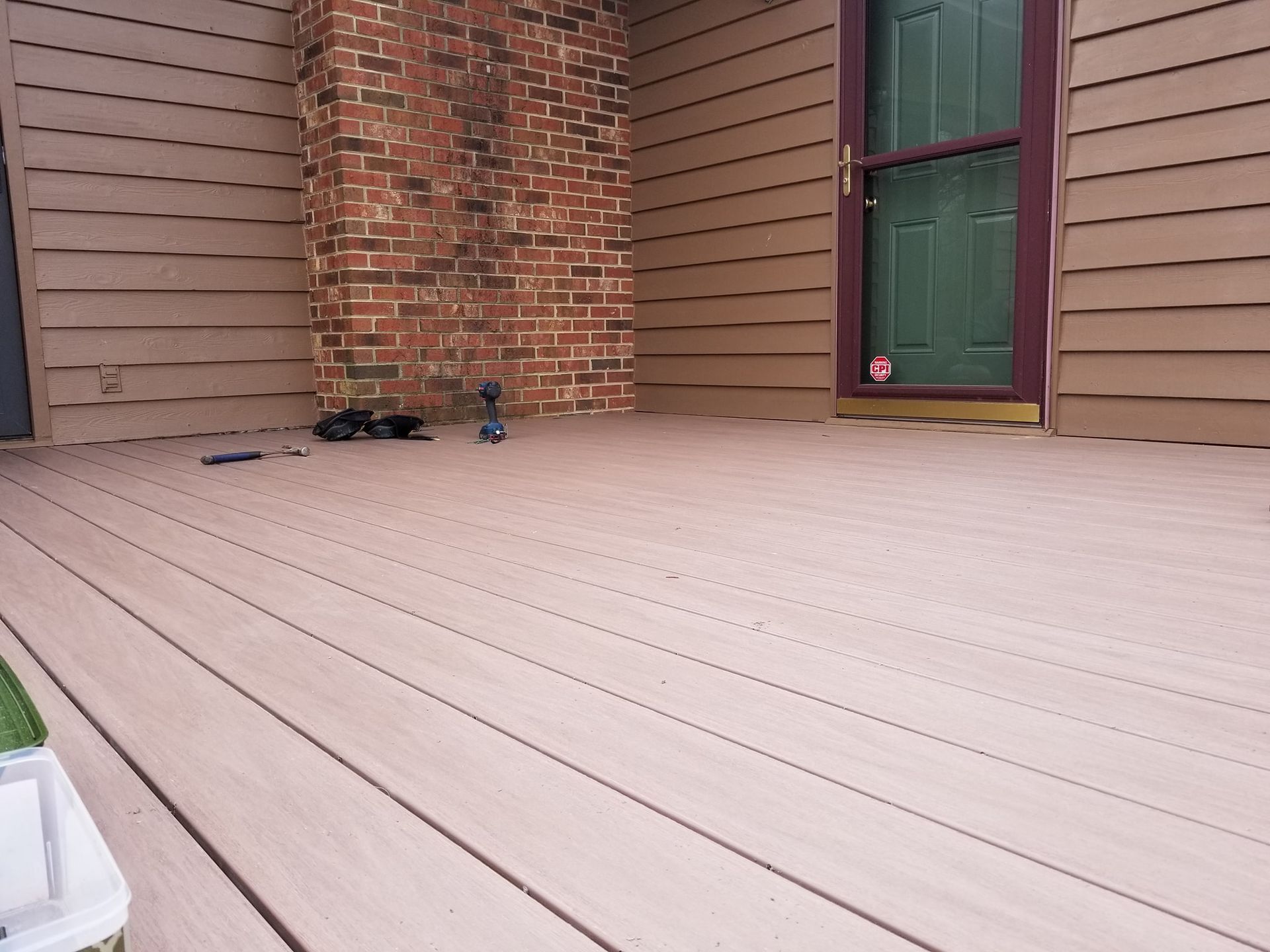 Wooden deck with a brick chimney and green door. A dark bird is standing on the deck.