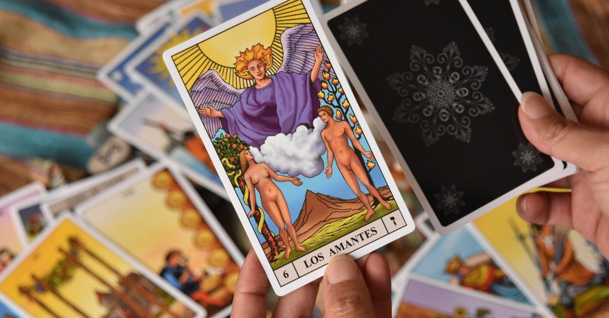Una mano sostiene cartas del tarot sobre una tirada, entre ellas El Emperador y una carta negra con un mandala blanco