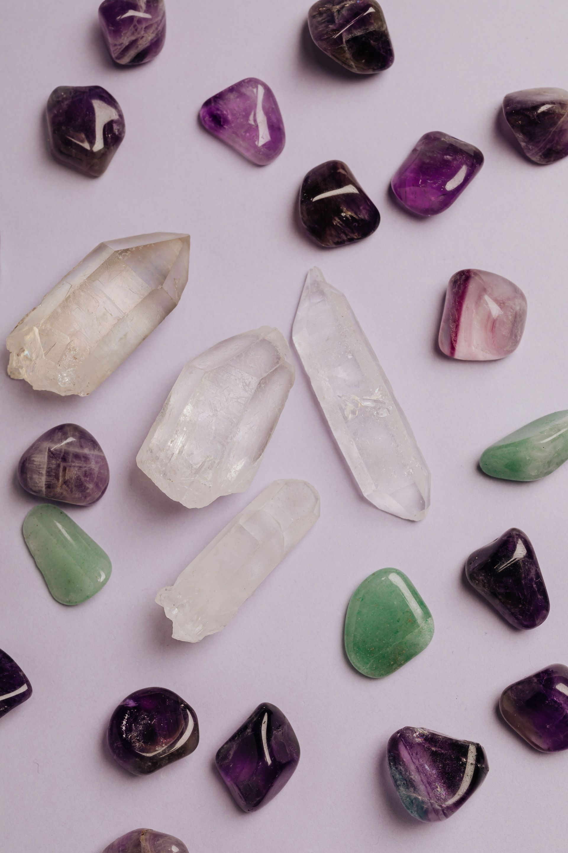 Gemas variadas de color morado, verde, blanco y transparente dispuestas sobre un fondo claro