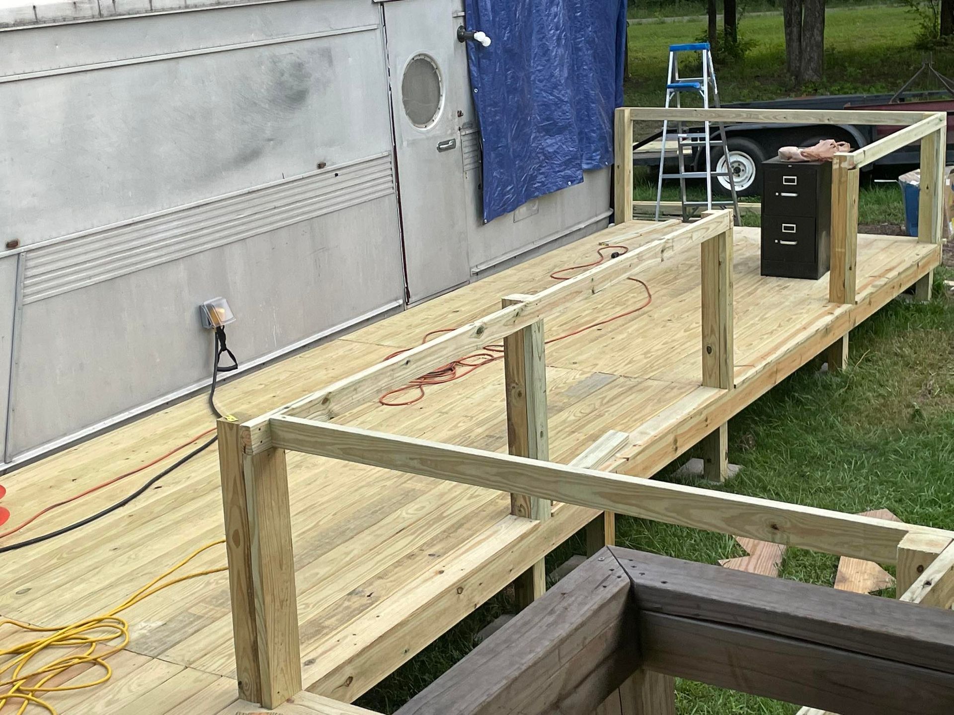 A newly constructed wooden ramp with railings leading up to the side of a trailer.