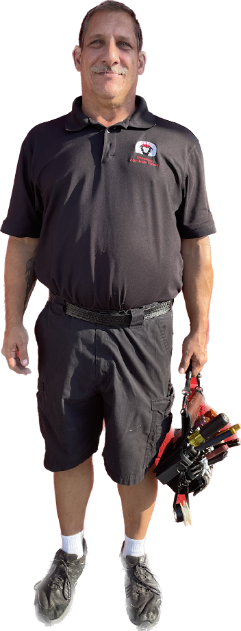 Man standing in black athletic shirt and shorts, holding golf clubs and wearing golf shoes.