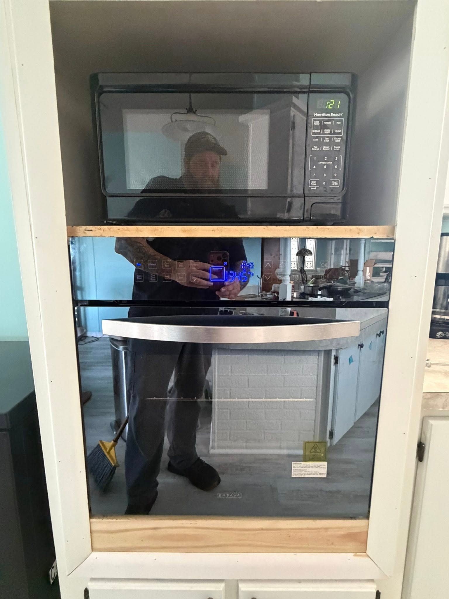 Built-in microwave above compact pull-out shelf in a kitchen cabinet cabinet opening