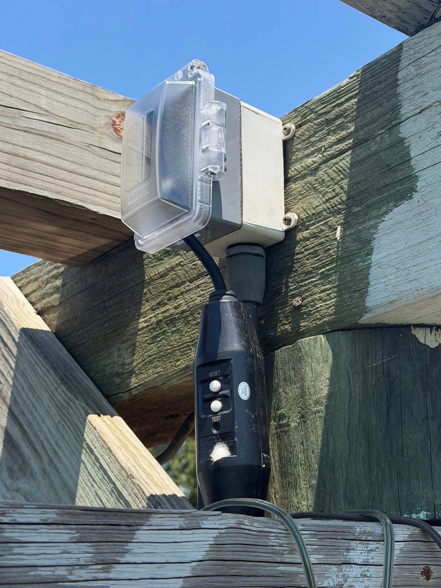 Close-up of a metal pole clamp mounted to a wooden deck rail outdoors.