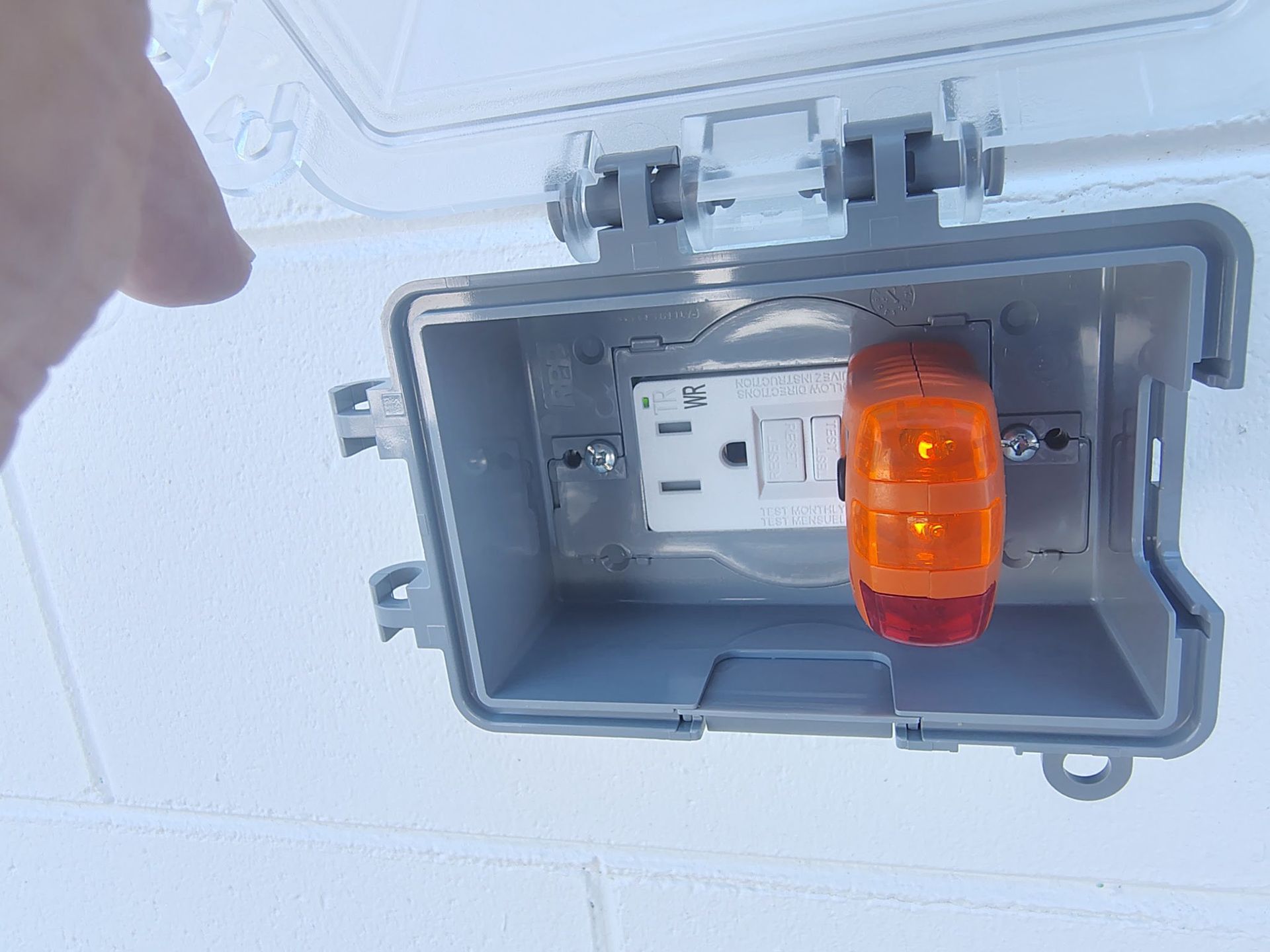 Outdoor electrical box with an outlet and an orange warning light inside, lid open